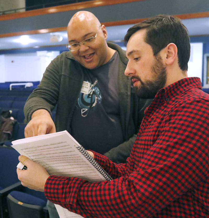 Woodstock High School graduate Alex Riak and band director Kevin Fredrick talk about a piece titled “Unknown” on Thursday, Dec. 7, 2023, during a rehearsal for the school's “Across the Universe” concert. Riak, who graduated in 2014 and now works as a professional composer in Los Angeles, created the piece for the concert.