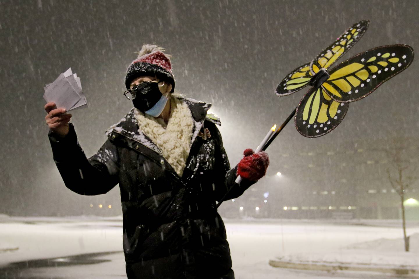 Sherry Liske reads a speech from her notecards during a candlelight vigil for ICE detainees outside of the McHenry County Government Center on Tuesday, Jan. 19, 2021 in Woodstock. A portion of the jail houses ICE detainees.  The vigil was hosted by members of Standing Up Against Racism and Elgin in Solidarity with Black Lives Matter and about 15 people attended the vigil despite heavy snowfall.