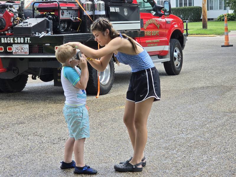 Emily Konczak helps Kaden Wiley put on a pair of googles Saturday, Aug. 3, 2024, during the Granville Days water fights at Hopkins Park.