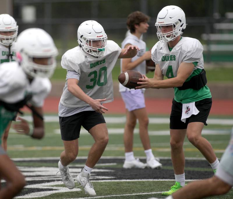 York quarterback Sean Winton (right) hands the ball off to teammate Jake Melion during practice at the Elmhurst school on Wednesday, Aug. 9, 2023.