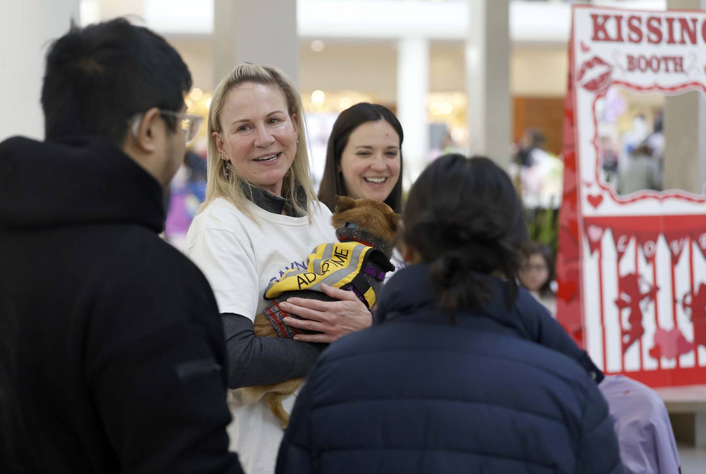 Amy Burchett, a board member of SAINRescue.org, talks Saturday to people about some of the animals available for adoption at the doggie kissing booth at Yorktown Center in Lombard.