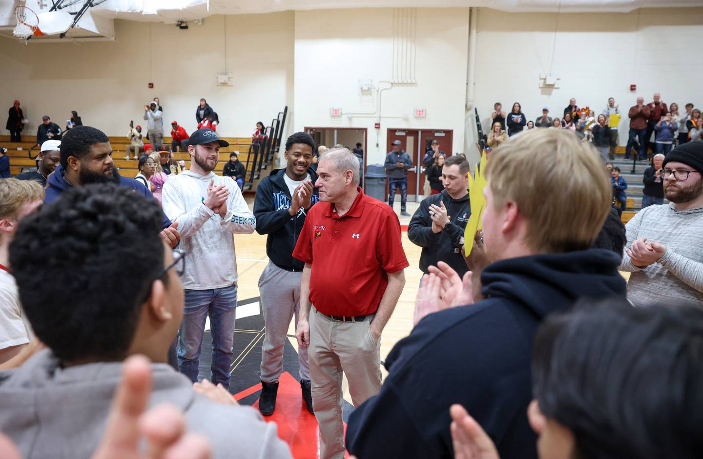 Surrounded by past and current players, St. Anne head coach Rick Schoon is applauded following his 500th career win after the Cardinals secured a 64-43 victory over Momence in the River Valley Conference semifinals on Tuesday, Feb. 10, 2026.