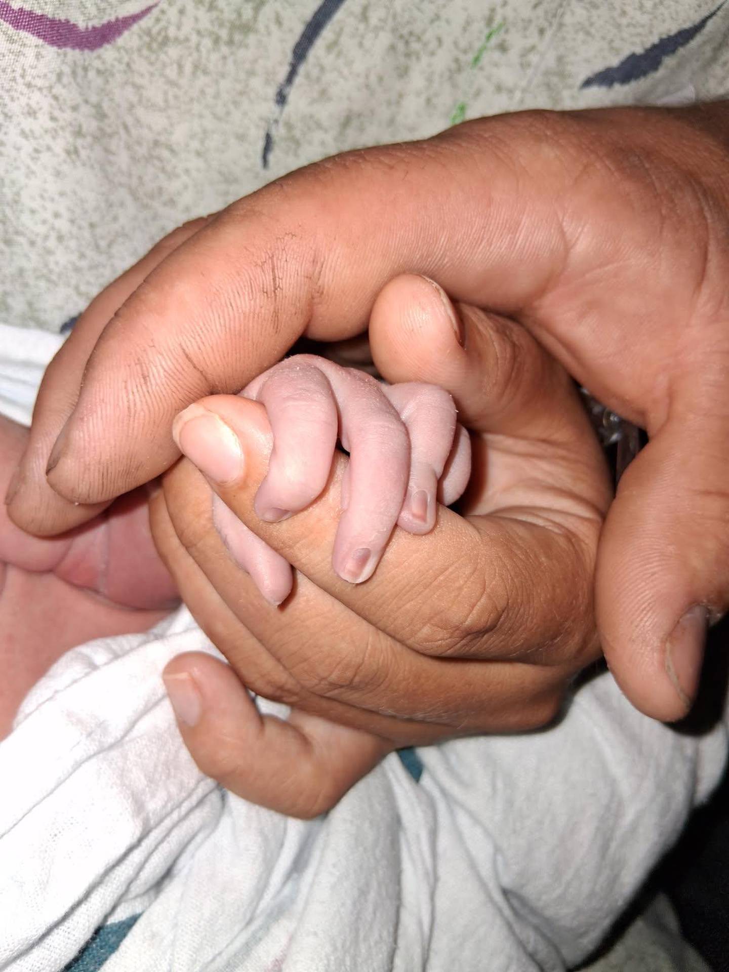 Lovina and Daniel hold baby Brooklyn's hand.