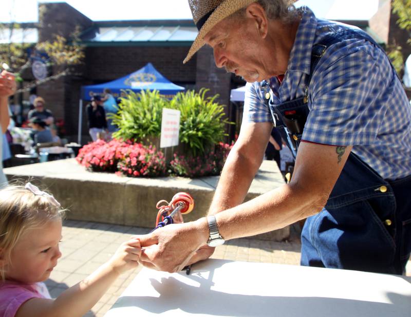 Bob Kaempfe, right, helps Finley Kay, 2, of Cary use an old-fashioned apple peeler during the Johnny Appleseed Festival in Crystal Lake Saturday.