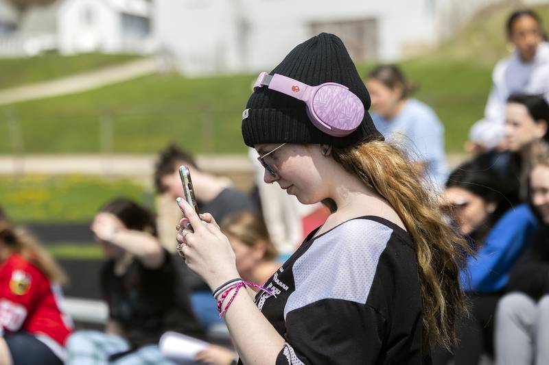 Adalyn Hitt, a junior at Dixon High School, records her burning house model Tuesday, April 22, 2025, outside of Dixon High School. The forensics class at DHS built houses then set them ablaze to study burn patterns as an arson investigation.