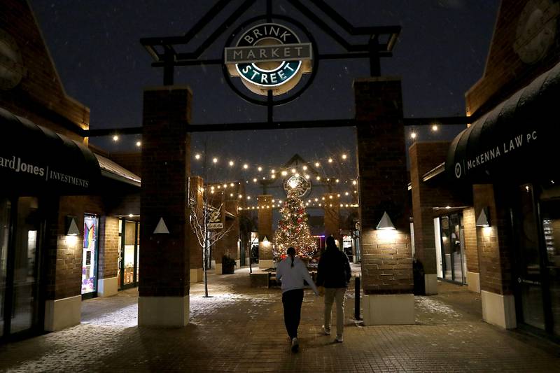 Couple walks through the Brink Street Market during Crystal Lake's Luminary Nights on Thursday, Dec. 19, 2024, in downtown Crystal Lake. The snowy night featured sidewalks lite luminaries, holiday shopping and a visit to the Santa House.