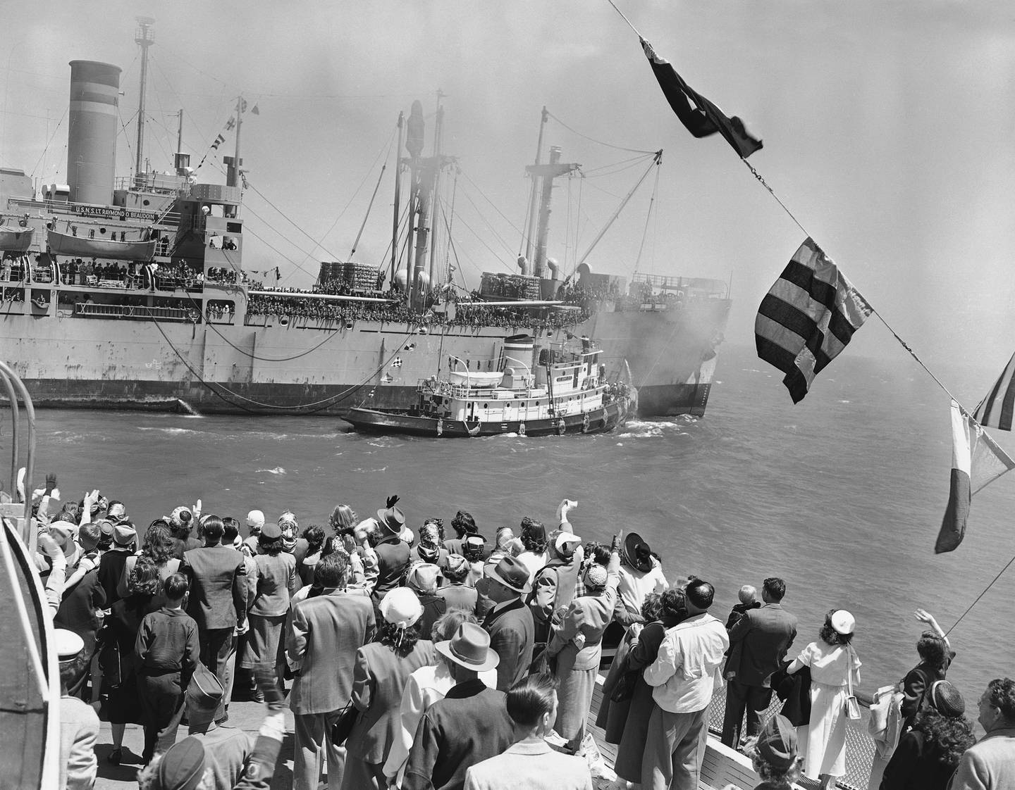 Friends and relatives aboard a ferryboat (foreground) wave as 1,422 Korean War soldiers reach San Francisco on May 15, 1951, on the USNS Lt. Raymond Beaudoin transport ship. Troops were returned under the rotation plan.