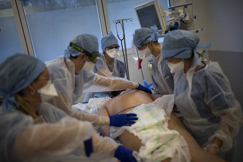 Medical workers turn over a COVID-19 patient on a ventilator in the COVID-19 intensive care unit at the la Timone hospital in Marseille, southern France, Friday, Dec. 24, 2021. (AP Photo/Daniel Cole)