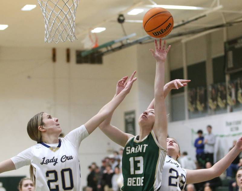 St. Bede's Ashlyn Ehm releases a shot under the hoop as Marqutte's Kaitlyn Davis and Nevaeh Corcoran defend during the Class 1A Regional semifinal game on Tuesday, Feb. 18, 2025 at St. Bede Academy.