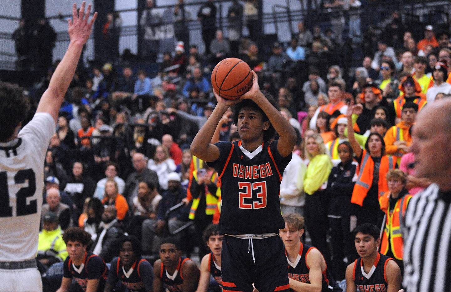 Oswego's Dasean Patton fires a three-point shot over Oswego East defender Ryan Johnson (23) during a boys’ varsity game at Oswego East High School on Friday, Dec. 9, 2022.
