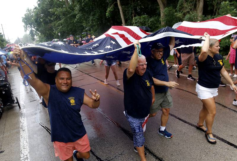 Ben Flores and other members of the Crystal Lake Lions Club flag team carry the American Flag on Sunday, July 7, 2024, during Crystal Lake’s annual Independence Day Parade on Dole Avenue in Crystal Lake. This year’s parade feature close to 100 units.