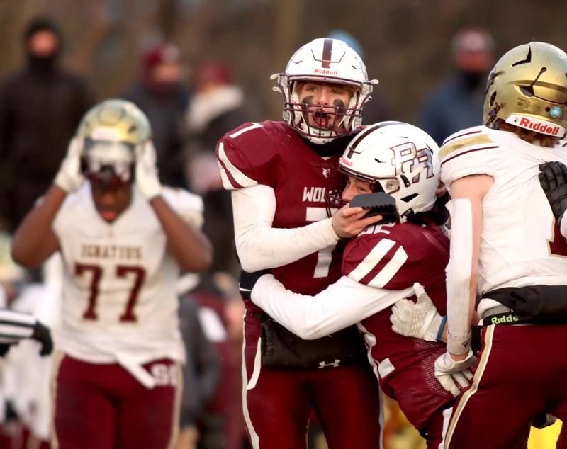 Prairie Ridge’s Tyler Vasey, center left, reacts with teammate Brogan Amherdt after Amherdt’s field goal clinched a win over St. Ignatius in Class 6A football playoff semifinal action at Crystal Lake on Saturday.