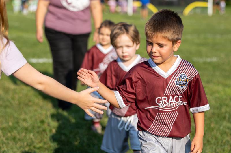 Wyatt Carretto high-fives friends and family attending the opening day ceremony of youth soccer on Saturday, Aug 16, 2025, at Peck Park in Ottawa.