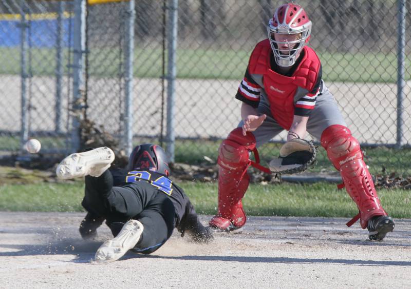 Somonauk's Brendan Roberts (24) dives into home plate to score a run as Earlville catcher Garett Cook (12) waits for the late throw on Thursday, April 14, 2022, in Somonauk.