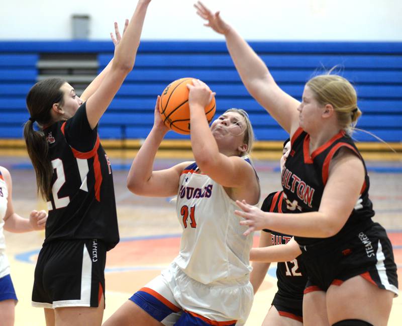 Eastland's Olivia Klinefelter (21) grimaces as she shoots against Fulton's Chloe Wilkin (22) and Kylie Smither (34) on Friday, Dec. 13, 2024 at Eastland High School in Lanark. Klinefelter scored 17 points and collected 10 rebounds in the Cougars 42-34 win.