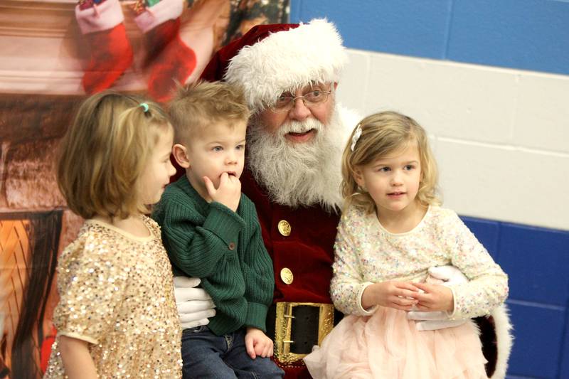 (From left) Siblings Spencer, 5, Michael, 2, and Penelope Messner, 3, of St. Charles sit on Santa Claus’ lap during a Breakfast with Santa hosted by the St. Charles Park District at the Pottawatomie Community Center on Monday, Dec. 12, 2022.