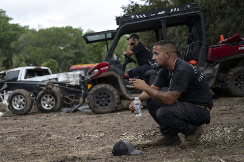 West Odessa Volunteer Firefighter Jed Wolske takes a smoke break while aiding in search and rescue efforts along the Guadalupe River, days after a flash flood swept through the area, Monday, July 7, 2025, in Ingram, Texas. (AP Photo/Eli Hartman)