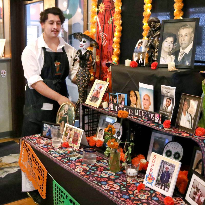 Tomas Zuniga, a waiter at El Jimador Mexican Grill, checks out the community ofrenda Tuesday, Oct. 31, 2023, that is set up at the restaurant in DeKalb. DeKalb will be hosting a Day of the Dead "Celebration of Life" Saturday, Nov. 4.