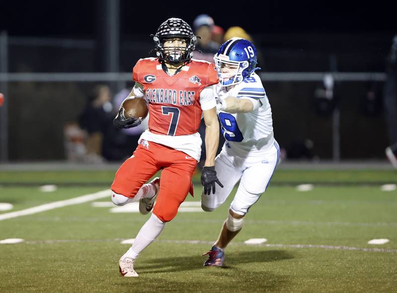 Glenbard East's Mike Orive (7) scrambles to escape Riverside Brookfield's Timothy Giacomelli Jr. (19) during the varsity football game between Riverside Brookfield and Glenbard East on Friday, Oct. 24, 2025 in Lombard, IL.
