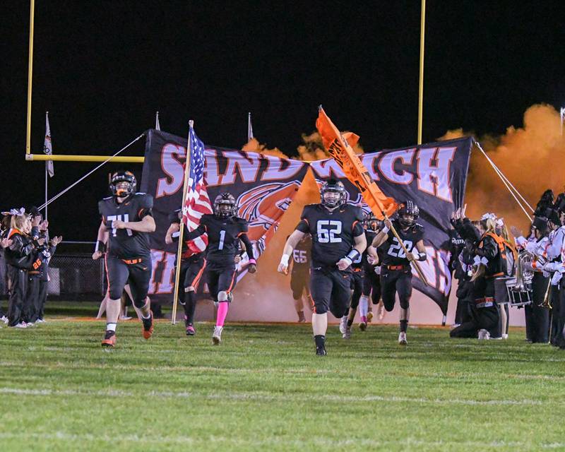 Sandwich football players run out onto the field for warm ups on Friday Oct. 25, 2024, before the start of the game as they took on Marengo High School.