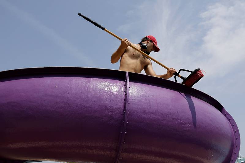 Lifeguard Jacob Brucker cleans a slide Wednesday, May 24, 2023, at the Woodstock Water Works Aquatics Center in Woodstock as the pool gets ready to open on Saturday.
