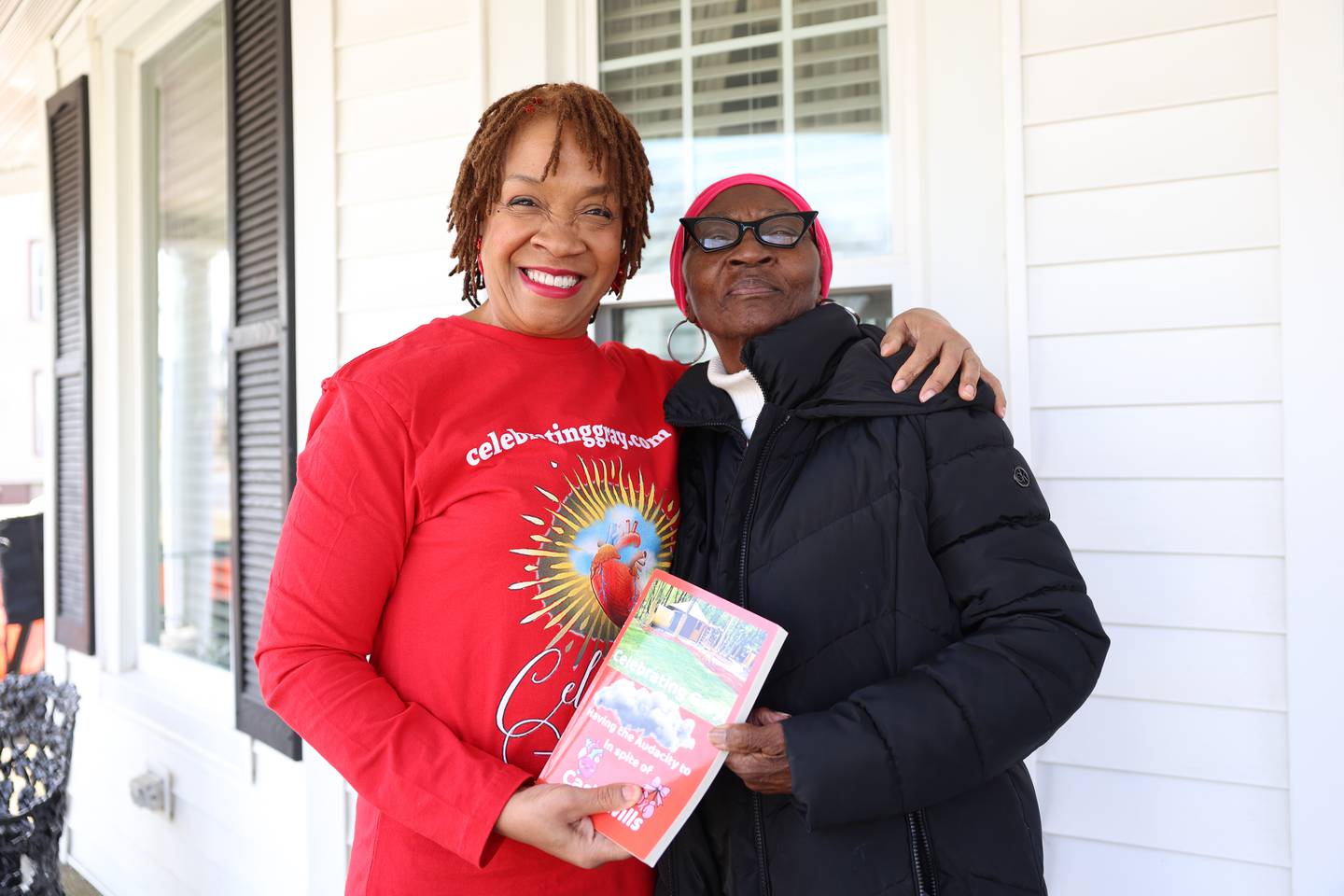 Carla Wills, left, stands with her former neighbor, Willa Smith, on the porch of Smith's North Greenwood Avenue home in Kankakee where she often sat as a young girl hoping to catch a glimpse of her mother across the street. That difficult time in her life inspired her to write a book she recently wrote, self-published and presented to Smith, titled “Celebrating Gray: Having the Audacity to in spite of.”