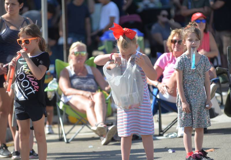 A kid checks her candy bag as she watches the parade with two friends during the Harvest Time Parade at Autumn on Parade on Sunday, Oct. 5, 2025 in Oregon.