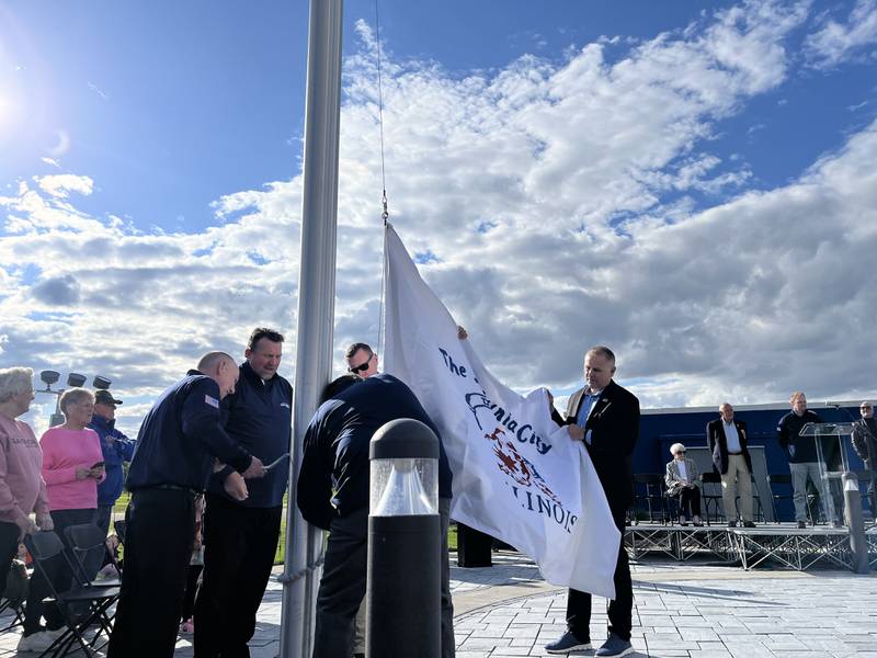 Dixon City Manager Danny Langloss (right) and Dixon Fire Chief Ryan Buskohl (middle left) raise Dixon's Petunia City flag at Raynor's ceremonious flag-raising event Thursday, May 22, 2025.