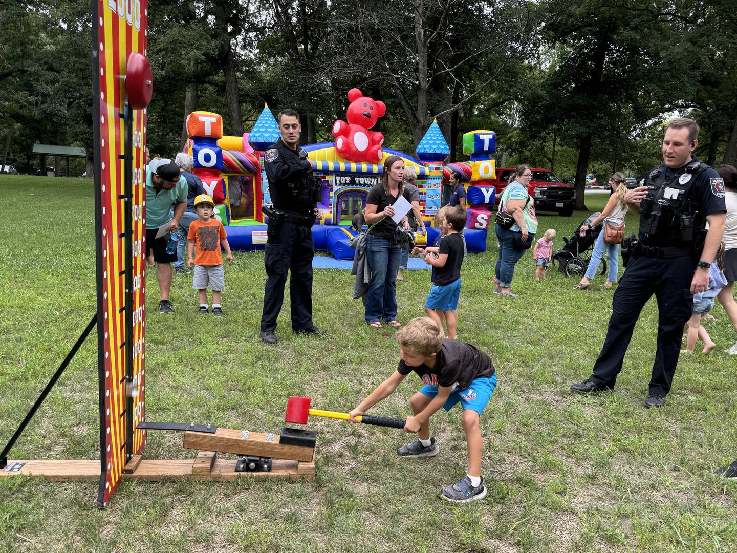 5-year-old Axel brings the hammer down on a target, ringing the bell with encouragement from Officer Tyler Mayerhofer.