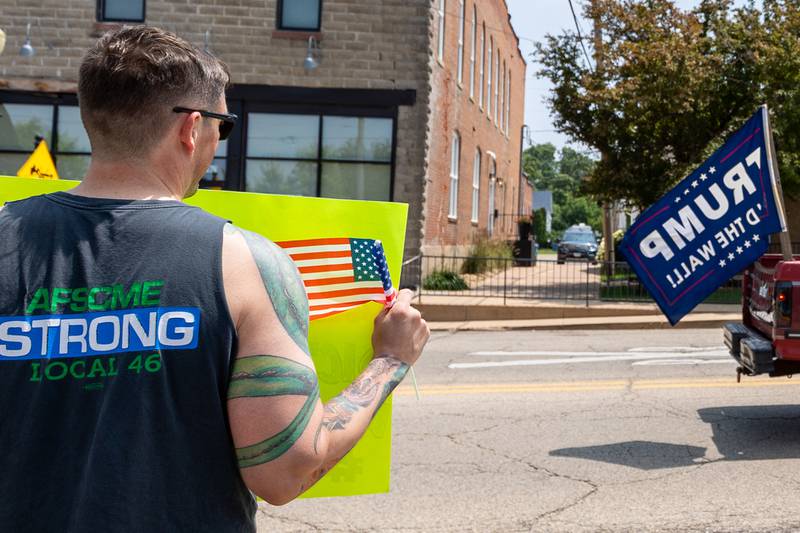 Protester holds sign as truck with Trump flag drives past honking on Saturday, June 14, 2025 at Rotary Park in Princeton.