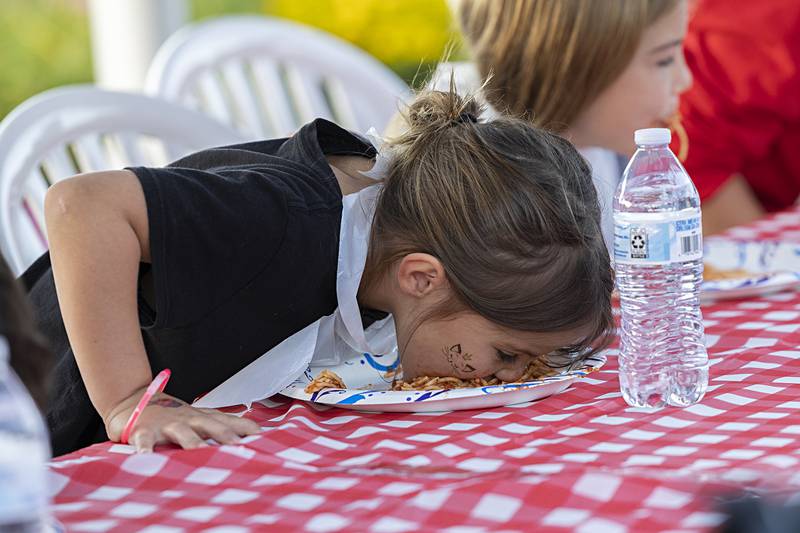 Breelyn Hill, 5, goes face first into a plate of spaghetti during an eating contest Saturday, Aug. 10, 2024 at Dixon’s Venetian Night.