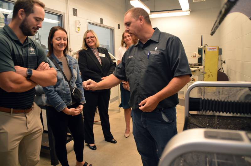 Fox shows Carroll and Black Bros. CFO Megan Kneebone a nameplate created by the water jet tool as IVCC President Dr. Tracy Morris and Heather Seghi, then Interim Dean of Workforce Development, look on.