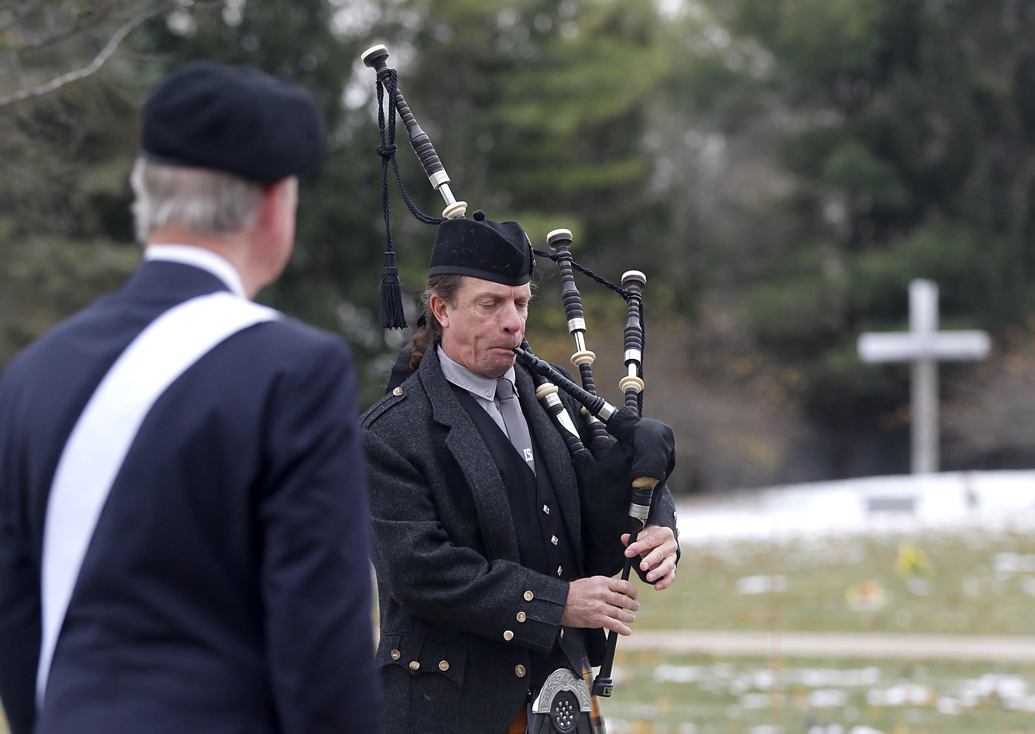 Bob Schafer listens as Tim Hess, of the Dundee Scottish Pipes, plays the bagpipes during the Veterans Day flag placement ceremony Tuesday, Nov. 11, 2025, at the gravesites of veterans at McHenry County Memorial Park Cemetery in Woodstock.