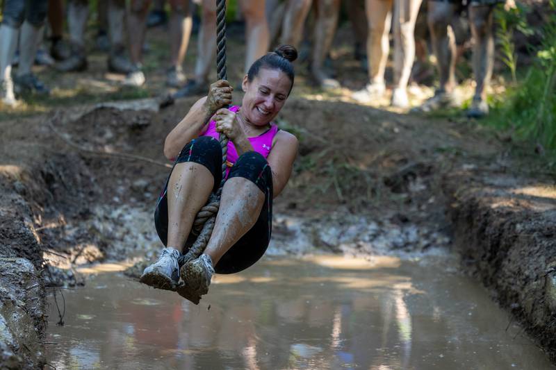 Participate of the 2025 Muddy Dash swings across mud pool on rope on Saturday, June 28, 2025 at Fox Valley Off Road in Utica.