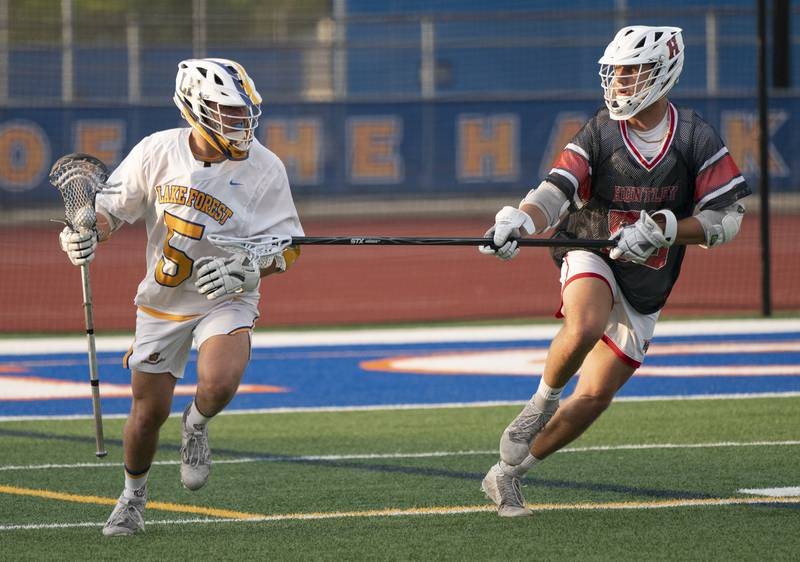 Lake Forest's Patrick Lee looks to pass past Huntley defender Ben Wiley during the boys lacrosse supersectional match on Tuesday, May 31, 2022 at Hoffman Estates High School.