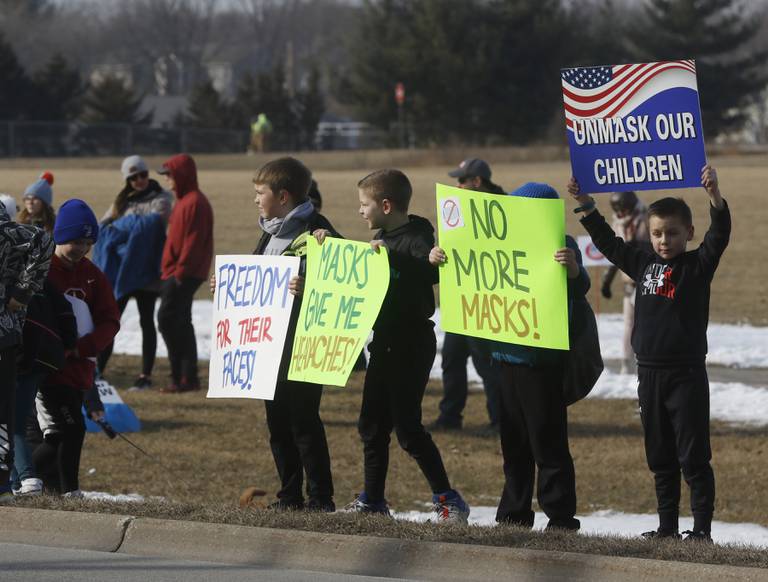 Children hold signs during a Cary School District 26 anti-mask rally Tuesday, Feb. 15, 2022, along Three Oaks Road at Cary-Grove Park. The event was attend by about 100 people and organized by the Illinois Parents Union Cary.