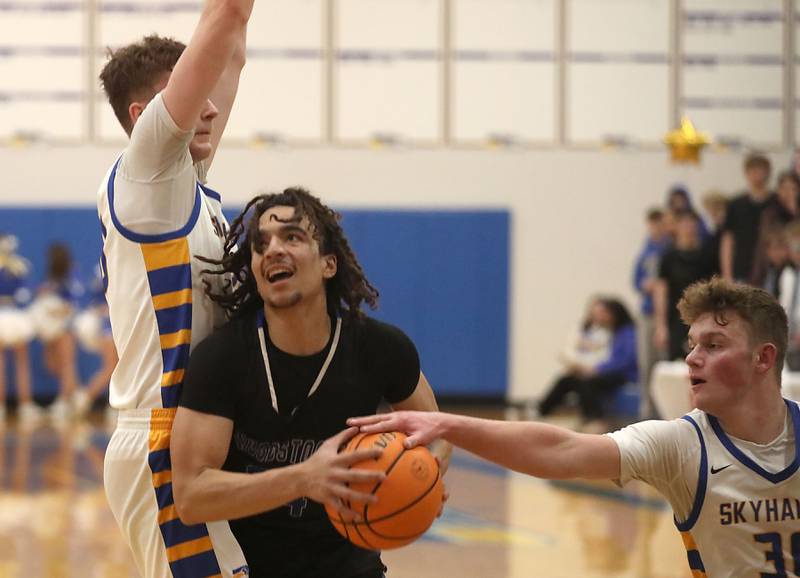 Woodstock's JJ Stokes (center) tries to drive to the basket between Johnsburg's Josh Kaunas (left) and Jayce Schmitt (right) during a Kishwaukee River Conference boys basketball game on Friday, February. 13, 2026, at Johnsburg High School.