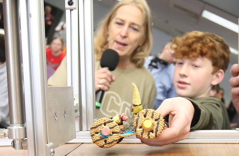 Collin Dever of La Moille Grade School, places his edible car onto the track as Illinois Valley Community College President and emcee Tracy Morris, watches during the 29th annual Edible Car Contest on Wednesday, Feb. 26, 2025 in the cafeteria at Illinois Valley Community College.