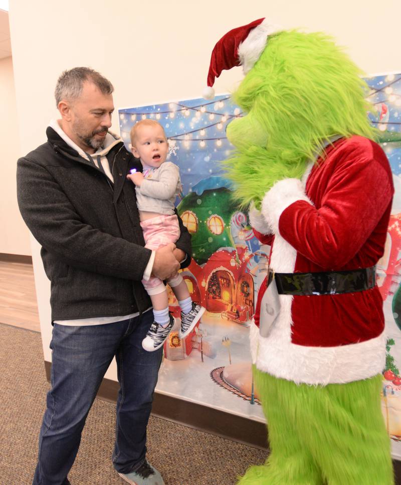 Tom Chlystek holds his daughter Julia while she reacts to seeing the Grinch while attending Downers Grove Park District's Candy Cane Lane Saturday, Dec. 2, 2023.