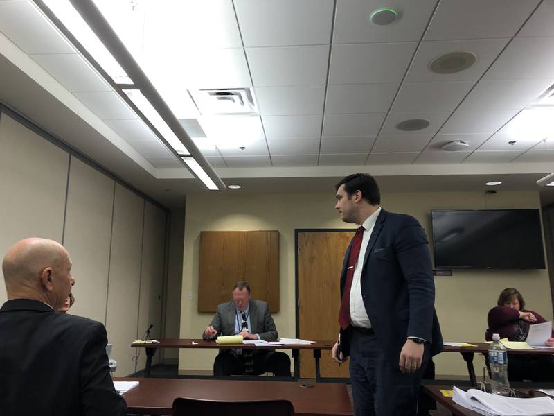 McHenry County board member Eric Hendricks gives case law documents to the McHenry County electoral board during an objection hearing Dec. 19, 2023