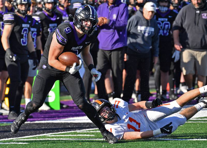 Downers Grove North’s Will Vala (9) sheds Lincoln-Way West tackler Maxwell White (11) after catching a pass during a Class 7A quarterfinal game on November 15, 2025 at Downers Grove North High School in Downers Grove .