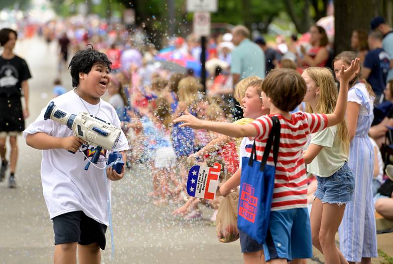 Kids along the parade route play in bubbles sprayed by a participant of the annual Wheaton Independence Day Parade on Thursday, July 4, 2024.