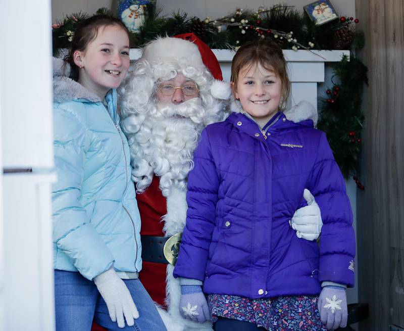 Sisters Bianca, 10, (left) and Miranda Ricca, 7, of Downers Grove take a photo with Santa Claus at the Gingerbread House in Downers Grove, Ill. on Sunday, Dec. 18, 2022.