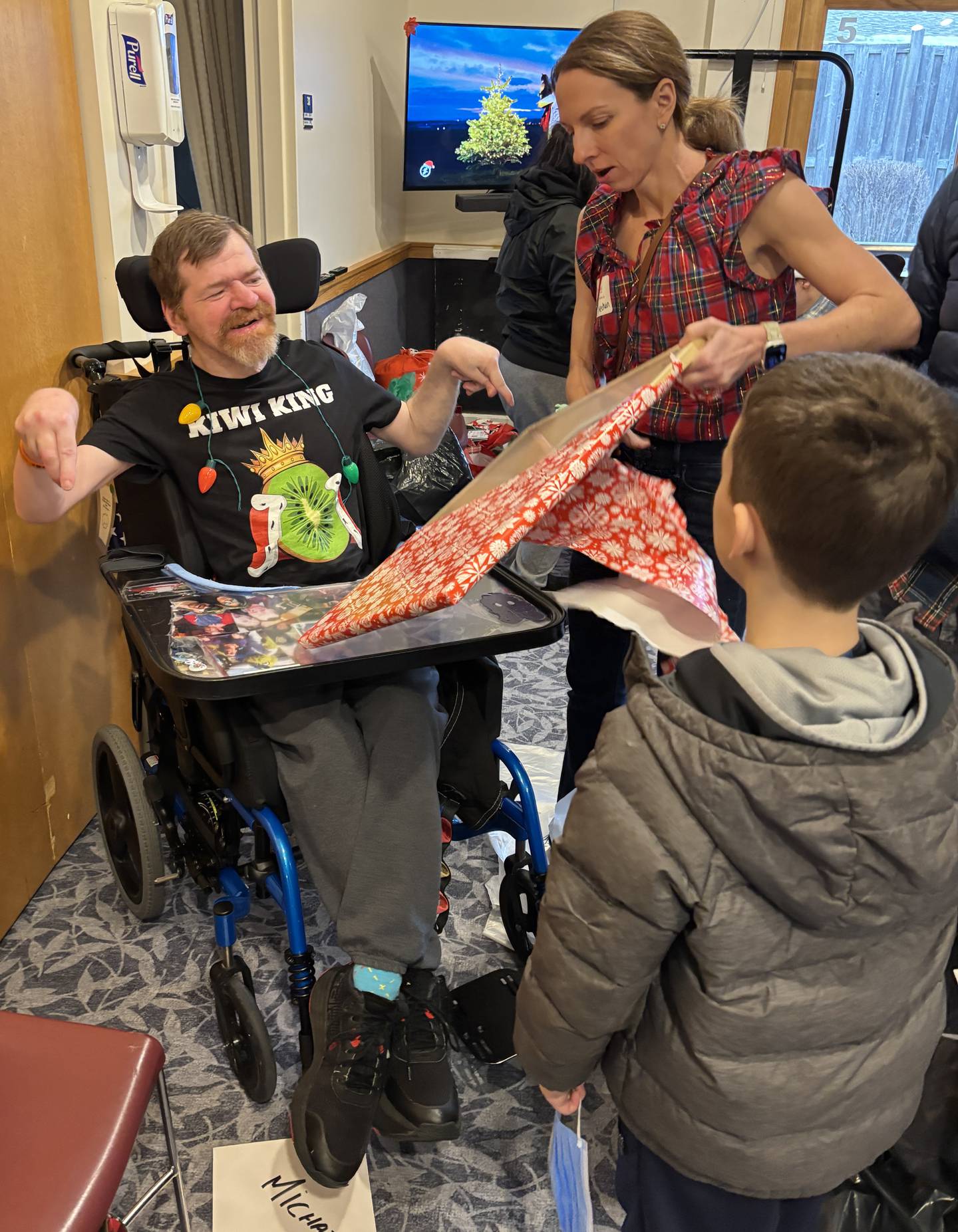 Volunteers assist Marklund resident Michael K. with opening one of his Christmas presents during the facility's annual gift opening event.
