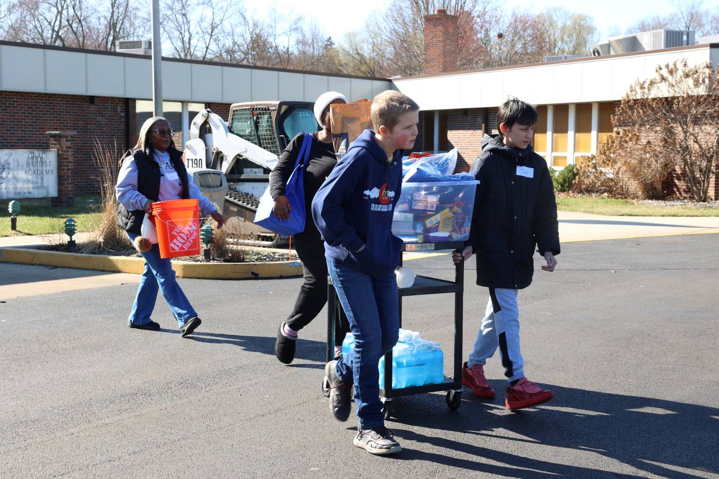 Volunteers Josiah Most, near, and Joel Norton, right, both sixth graders at Grace Christian Academy, help local residents bring supplies to their vehicles at the school on Thursday, March 12, 2026, following the EF-3 tornado that tore through Kankakee County on March 10. The school, which is on the outskirts of Aroma Township along Waldron Road, canceled classes in order to become a supply and meal hub for those impacted by the storm.
