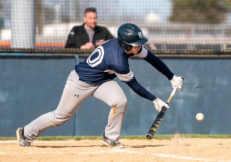 Plainfield South's Caleb Arndt (10) bunts the ball driving in a run against Oswego during a baseball game at Oswego High School on Monday, April 11, 2022.