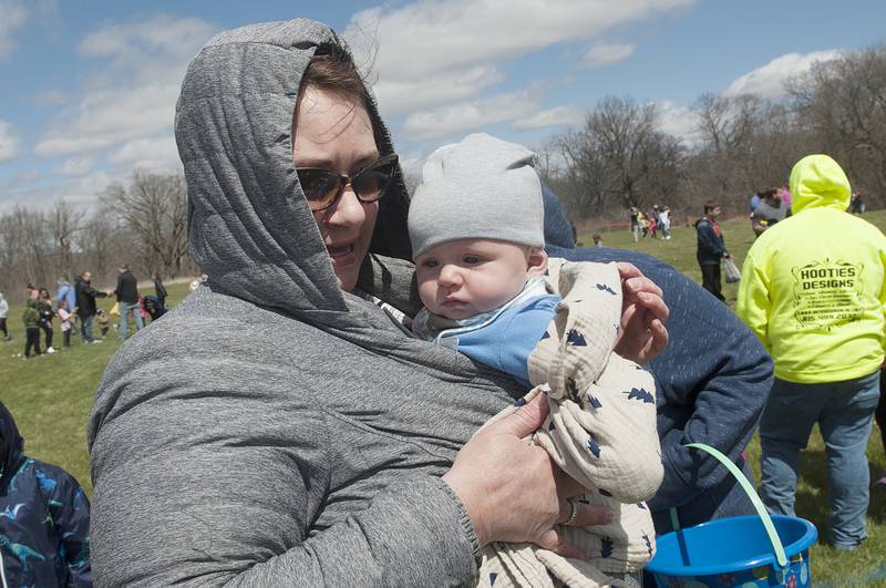 Grandma Monica Rasmussen keeps five-month old Luka Zorek warm for his first egg hunt.