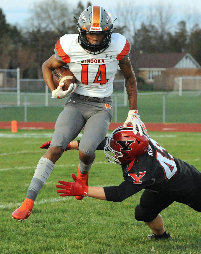 Minooka wide receiver Malik Armstrong (14) leaps through the grasp of Yorkville defensive back Blake Kersting (43) during a varsity football game at Yorkville High School on April 9.