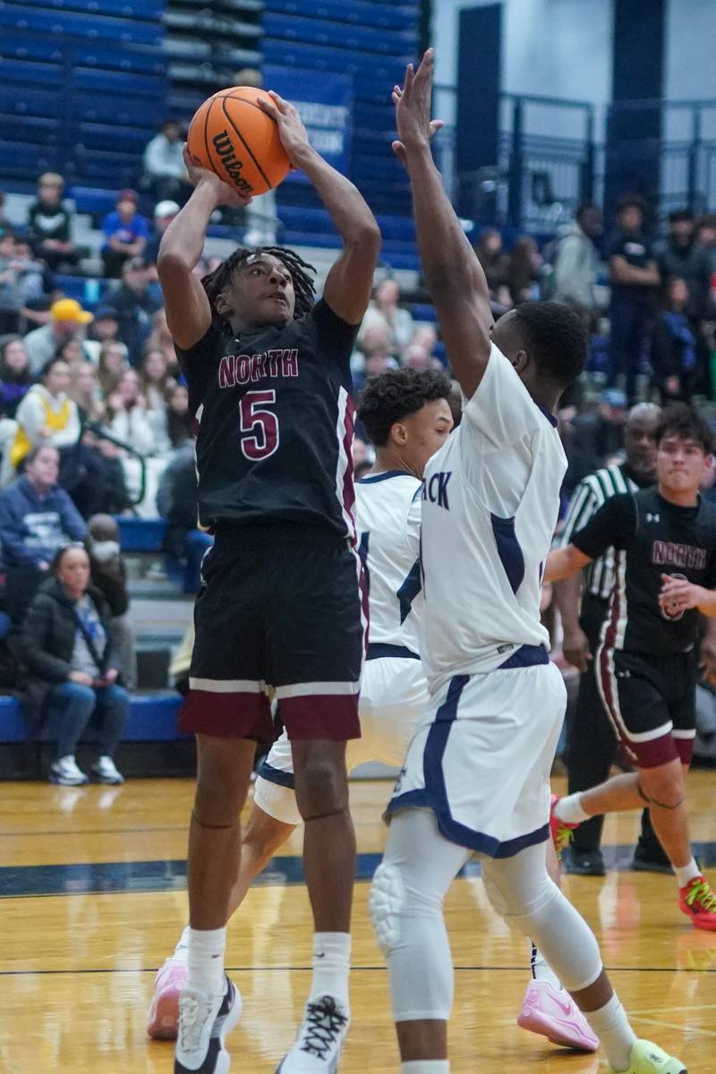 Plainfield North's Darin Ashiru (5) shoot the ball against Oswego East's Reginald McWaine (11) during a basketball game at Oswego East High School on Friday, Dec. 6, 2024.