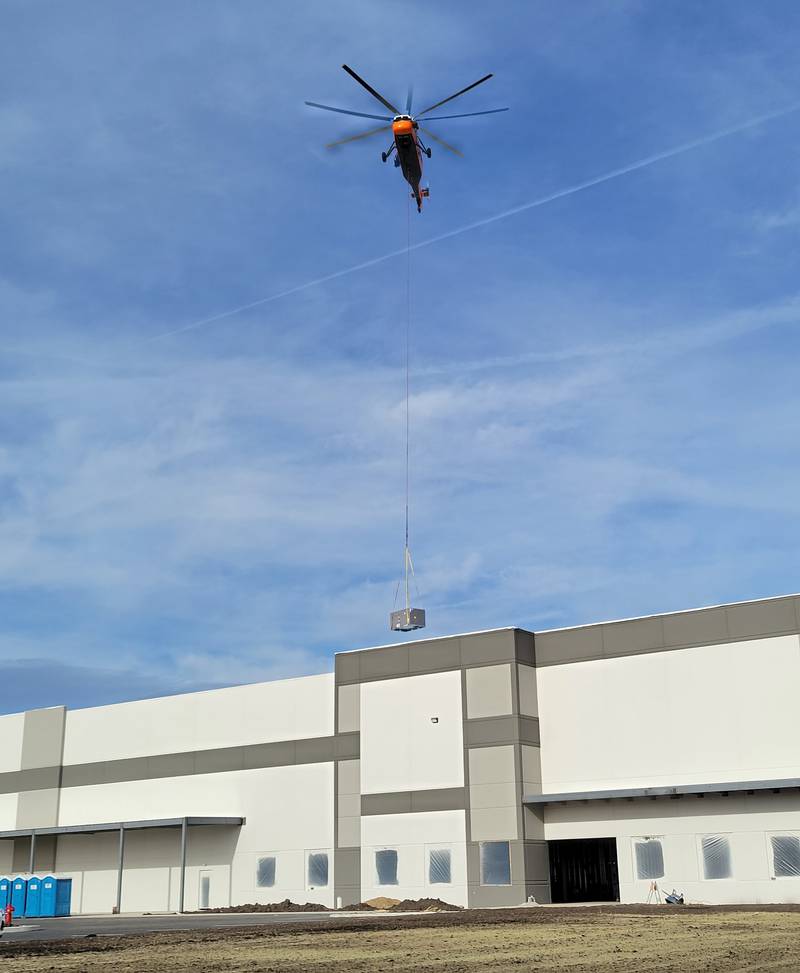 A 1962 Sikorsky helicopter lifts one of 10 heating and air conditioning units onto the roof of the new Ollie’s Bargain Outlet warehouse near the intersection of Interstate 80 and Illinois Route 26 in Princeton on Friday morning. The helicopter, according to an employee of Midwest Helicopters in Willowbrook, has a maximum lifting capacity of 5,000 pounds, so it managed to handle with ease the units that ranged in weight from 1,000 to 2,500 pounds in less than half an hour.